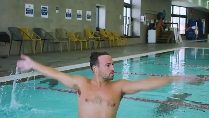 מאמן מדגים תנועת ידיים בבריכה